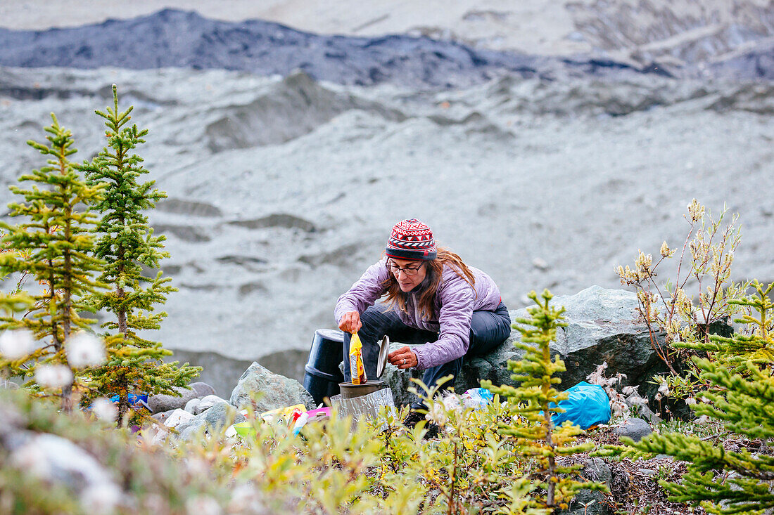 Woman Preparing Dinner In Camp Above The Root Glacier In Alaska, Usa