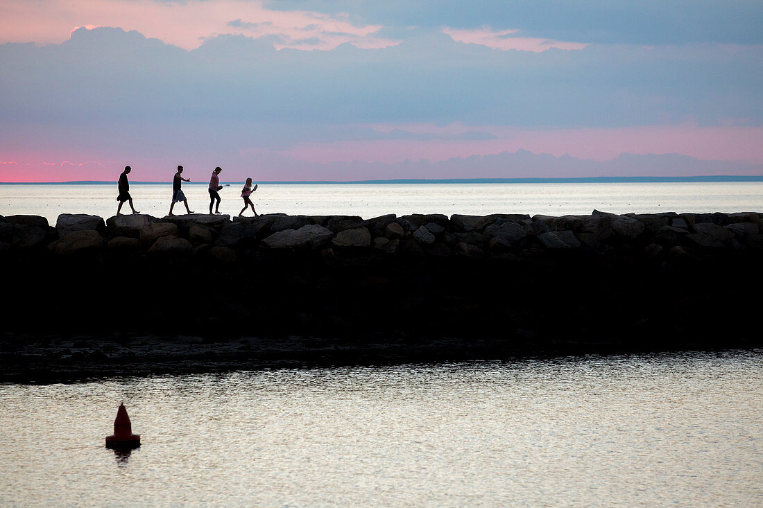 Silhouette Of A Family Walking On A Jetty During Sunset