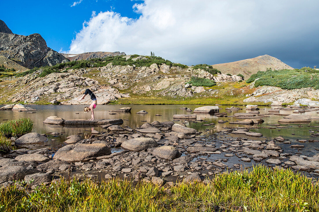 Young Woman Practices A Handstand On A Rock In The Mountains Of Colorado