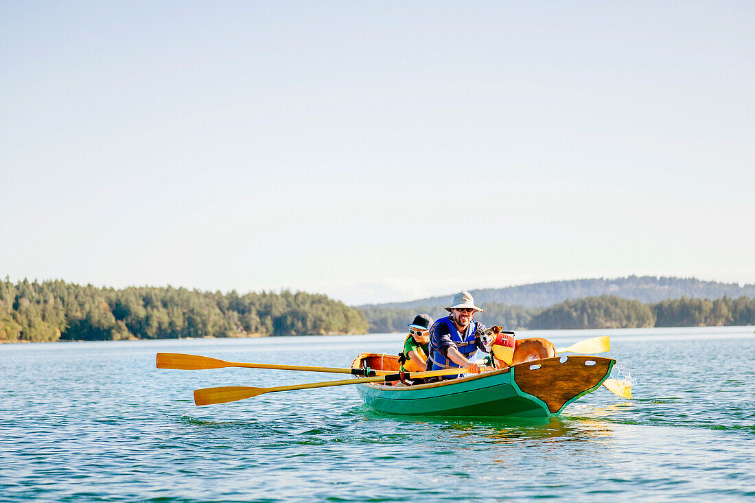 A Man With His Son And Their Dog In A Rowing Boat In Deer Harbor, Orcas Island, Washington, Usa