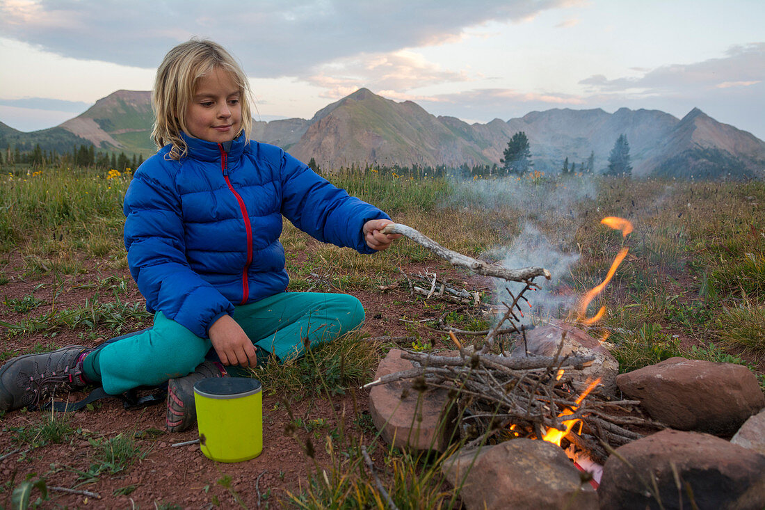 Young girl starting campfire along Colorado Trail near Trout Lake and Kennebac Pass in San Juan National Forest