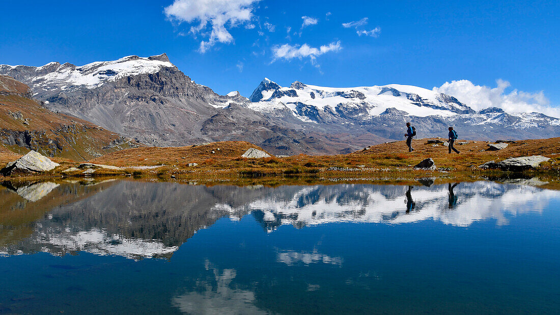 Monte Rosa mirrored in the lake with trekkers, valtournenche, Aosta Valley, Italy