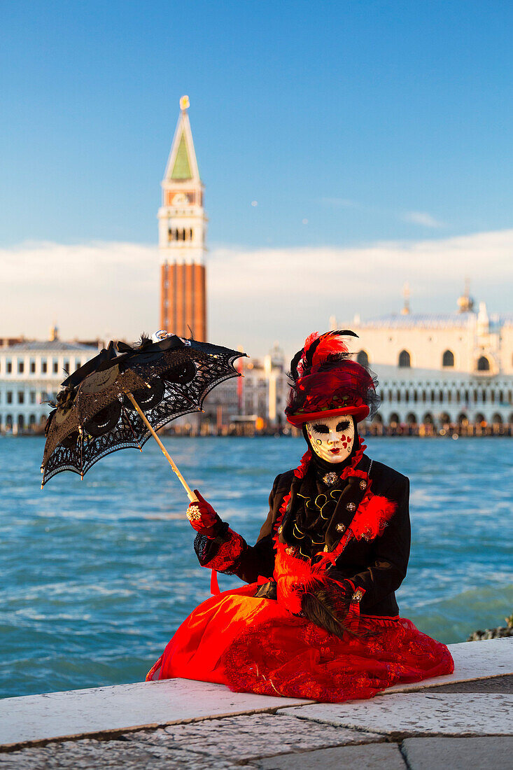 Porträt der Frau mit roten Kostüm und typische Maske des Karnevals von Venedig mit Markusplatz im Hintergrund Veneto Italien Europa