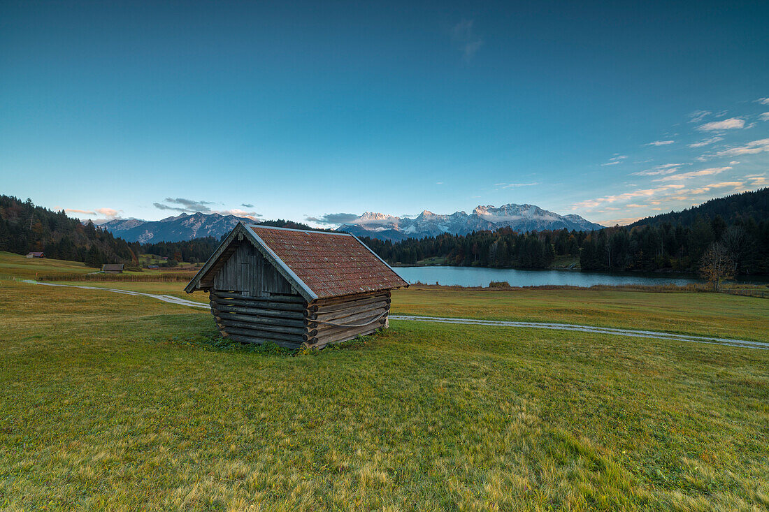 Wooden hut frames the alpine lake surrounded by the Alps Geroldsee Krün Garmisch Partenkirchen Upper Bavaria Germany Europe