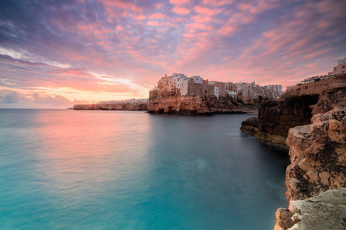 Pink sunrise on the turquoise sea framed by old town perched on the rocks Polignano a Mare province of Bari Apulia Italy Europe