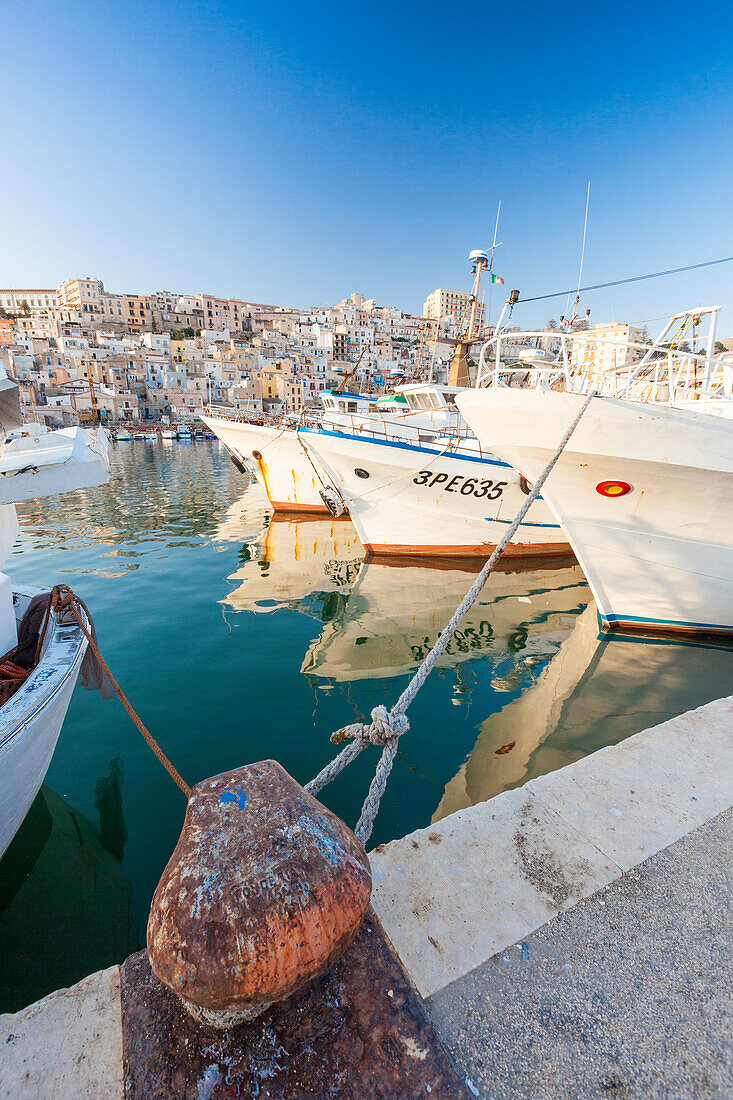 Fishing boats moored in the harbour surrounded by blue sea and the old town Sciacca province of Agrigento Sicily Italy Europe