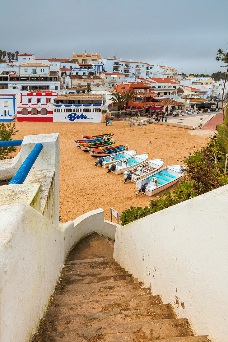 Boats on sandy beach frame the typical fishing village of Carvoeiro Lagoa Municipality Algarve Portugal Europe