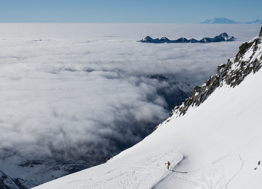 Skier over the clouds at Sella di Pioda, Valmasino, Valtellina, Lombardy, Italy, Alps