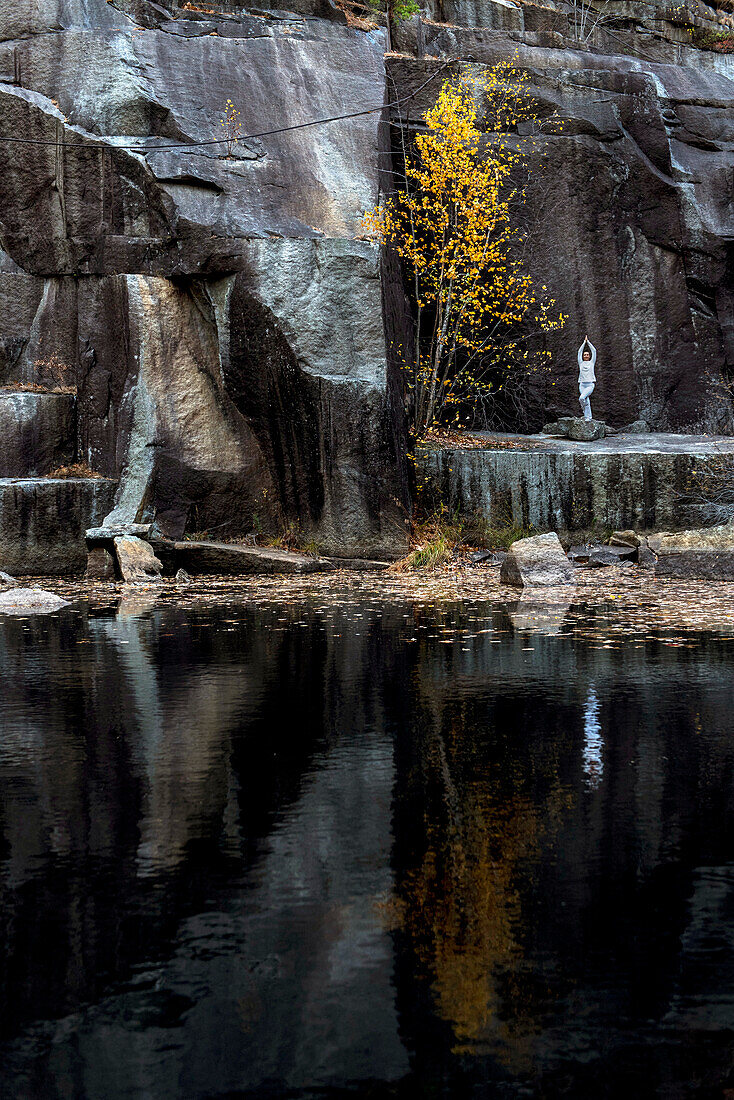 A Yoga Instructor Posing Near A Pond And Colorful Tree