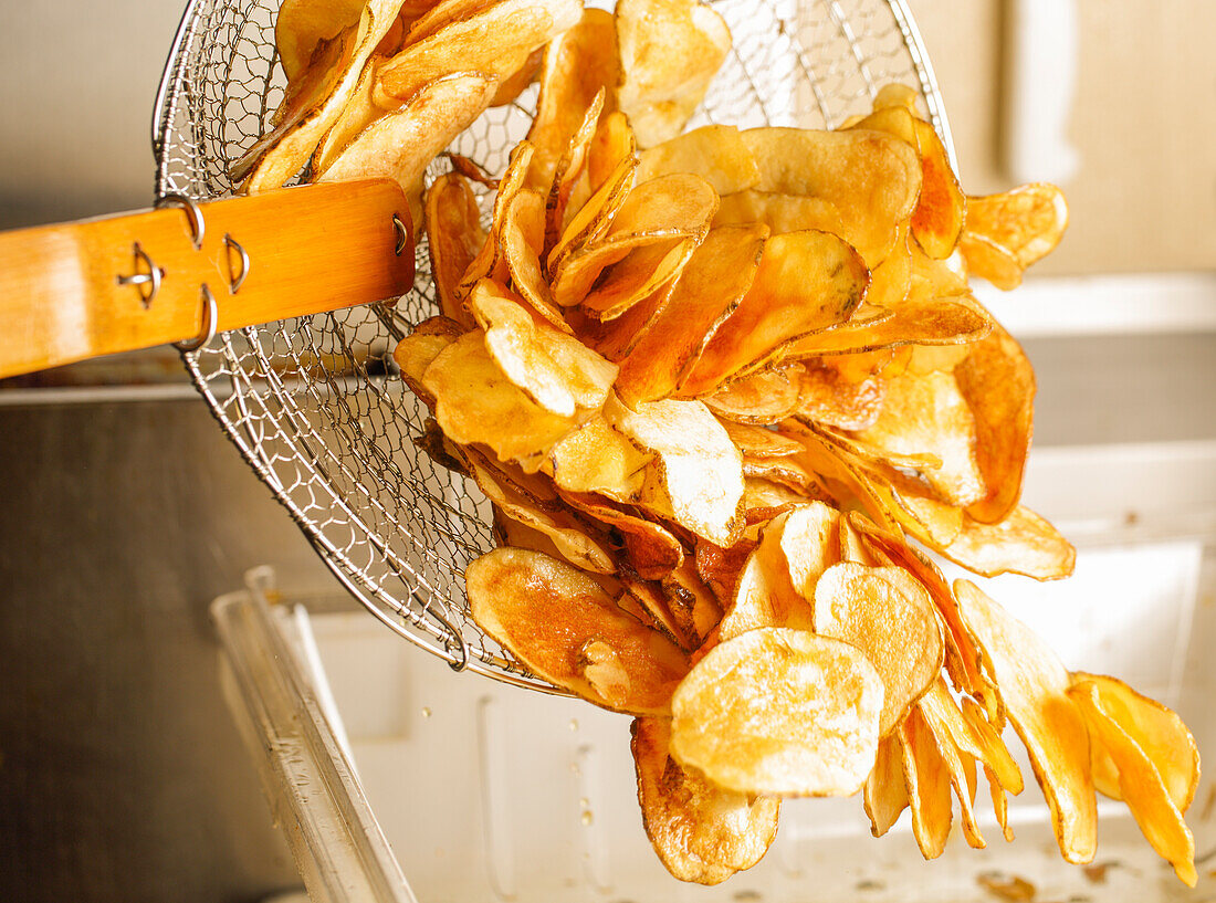 Feshly-Fried Potato Chips Being Poured Out Of A Fryer Basket