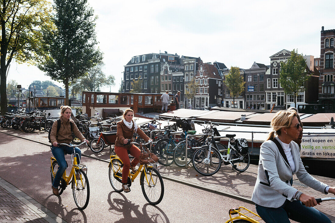 Junge Frauen auf Fahrrädern im Zentrum entlang des Kanals, Amsterdam, Niederlande, Europa