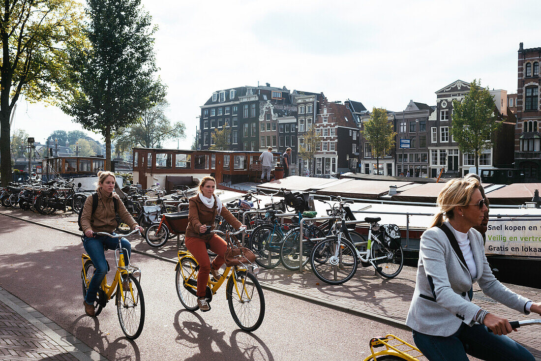 Young women riding bicycle in the Center along the Canal, Amsterdam, Netherlands, Europe
