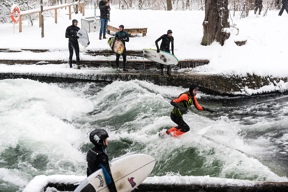 Surfing the Eisbach during Snowfall in English Garden, Munich, Germany