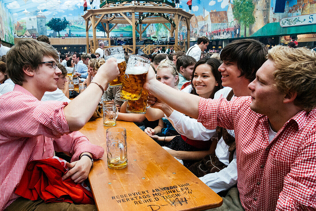 Feiernde stoßen mit ihren Bierkrügen an, Oktoberfest, München, Deutschland