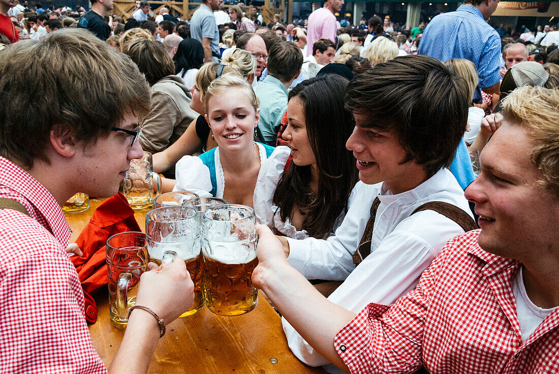 Revelers raise their beer mugs to toast at Oktoberfest, Munich, Bavaria, Germany