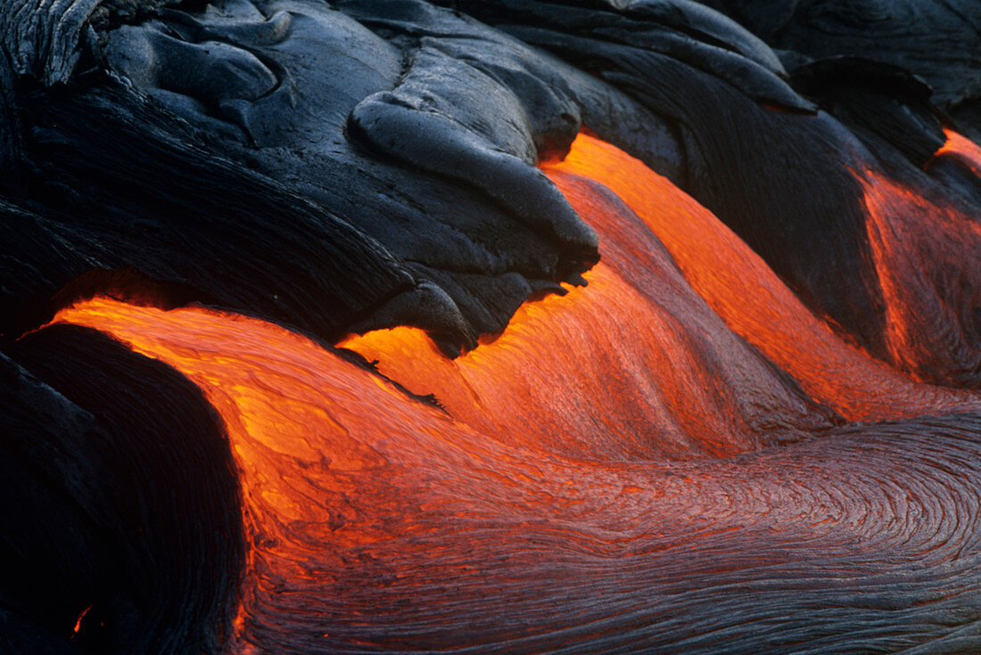 USA, Hawaii, Volcanoes National Park,  Glowing stream of molten lava pours breaks out during eruption of Kilauea volcano