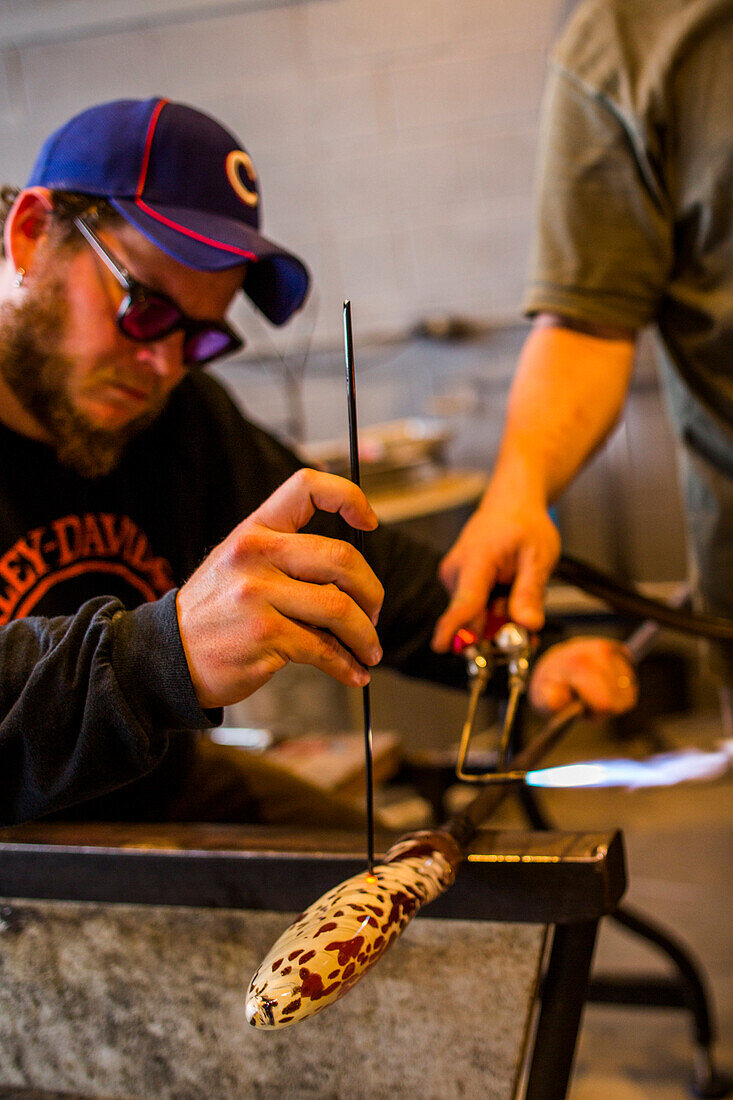 At a glass blowing studio on Whidbey Island, WA, a man makes a glass sculpture.