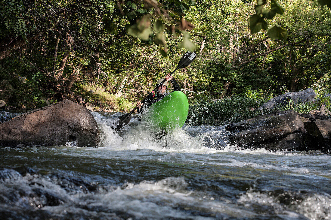 Kayaker boofing a rapid