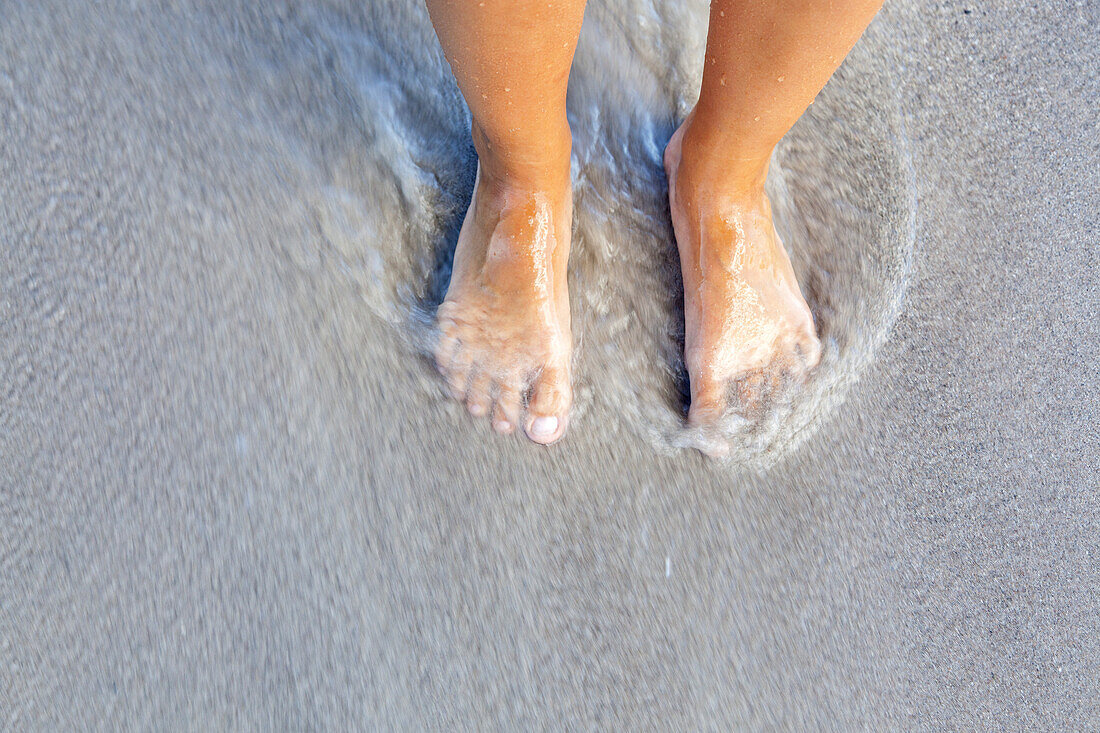 Feet on the beach in the sea