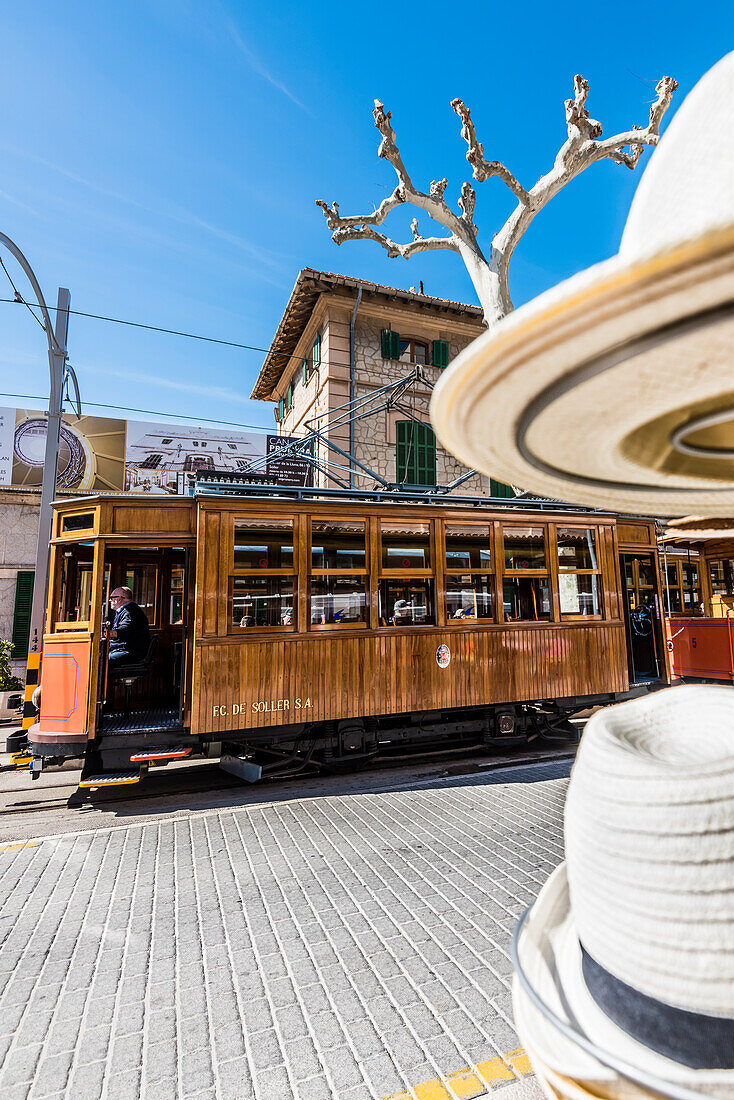 The famous ancient tram between Port de Sóller and Sóller drive past a store with hats, Port de Sóller, Mallorca, Spain