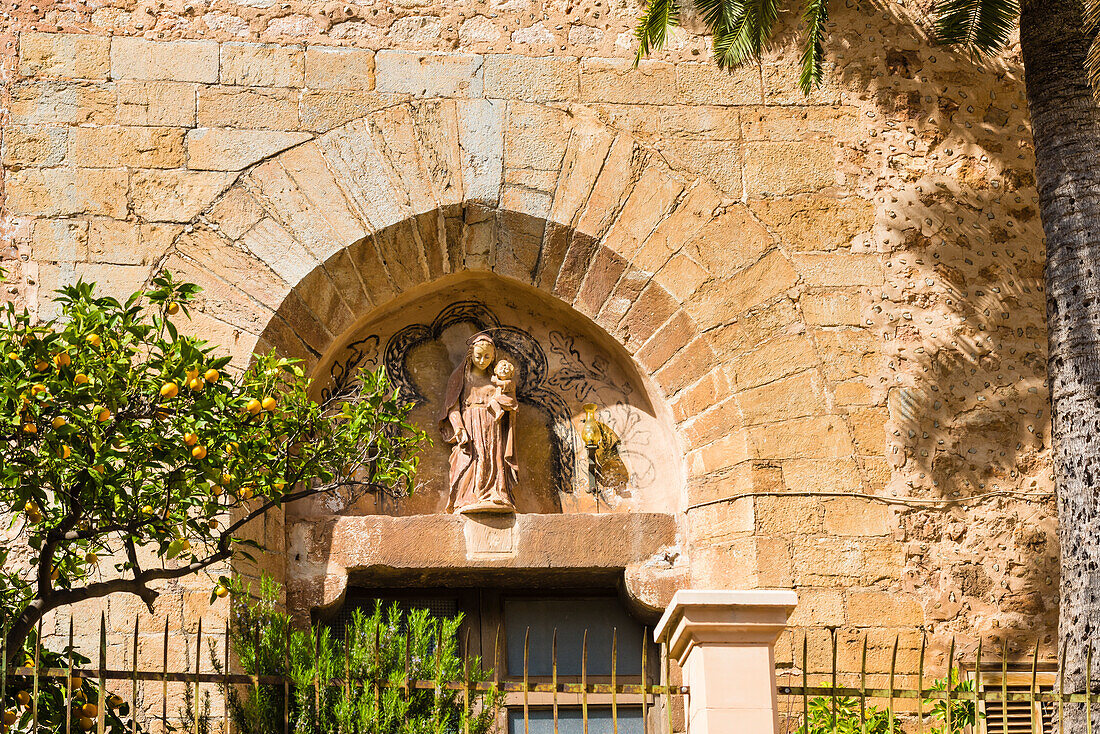 Portal mit Figur und Orangenbaum der Dorfkirche im malerischen kleinen Bergdorf im Tramuntanagebirge, Fornalutx, Mallorca, Spanien