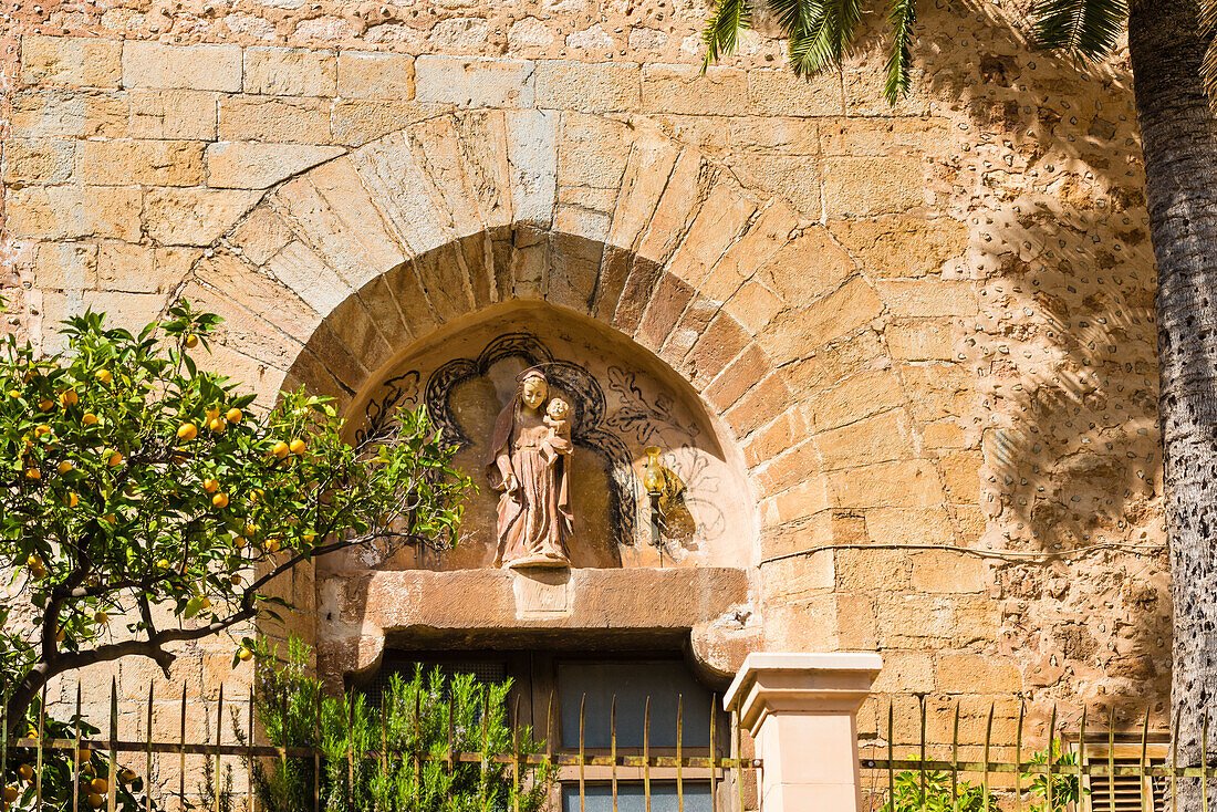 Portal with figure and orange tree at the village church in the picturesque small mountain village in the Tramuntana Mountains, Fornalutx, Mallorca, Spain