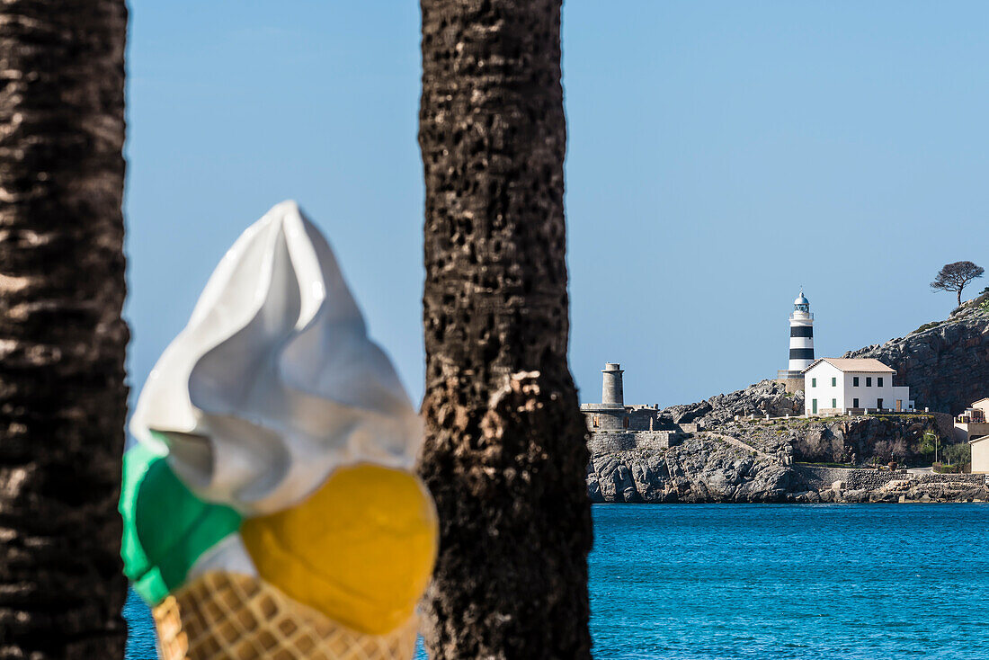 A big wafer cone as an advertisement in the harbour with view at the lighthouse, Port de Sóller, Mallorca, Spain