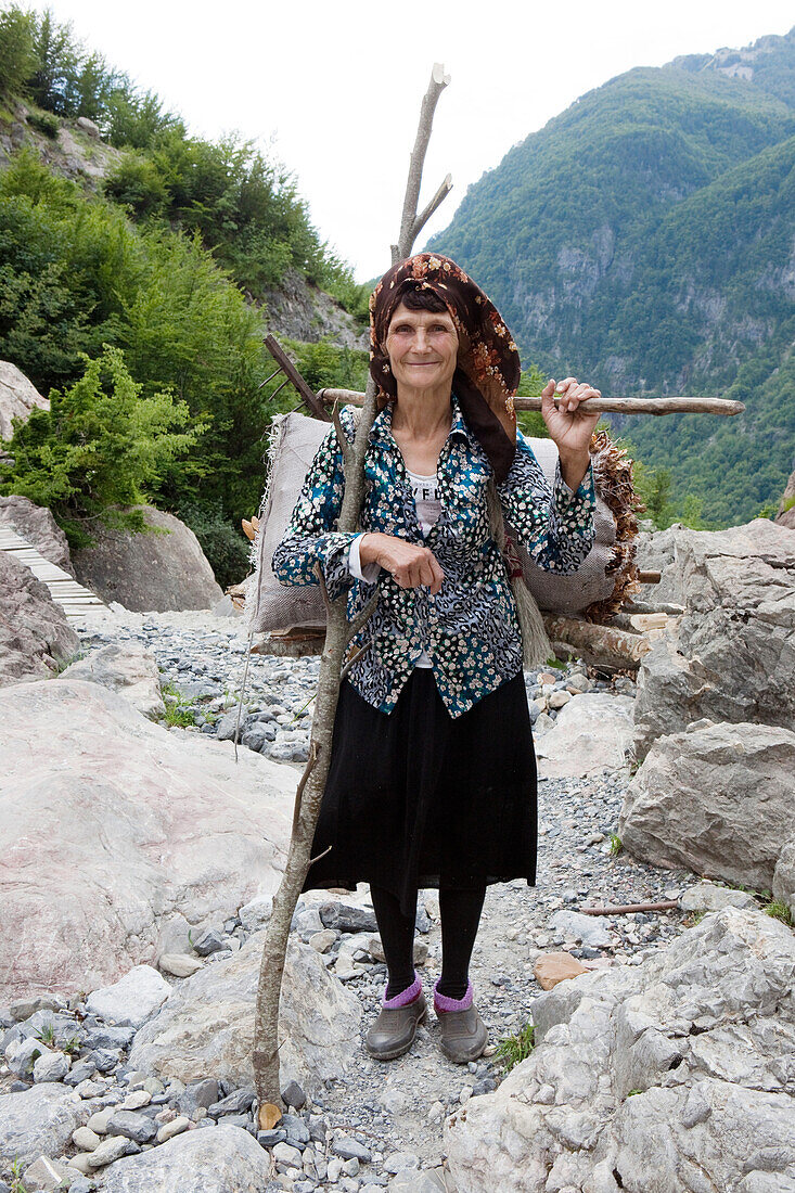Alte Frau trägt Feuerholz auf dem Rücken, Theth, Albanische Alpen, Albanien