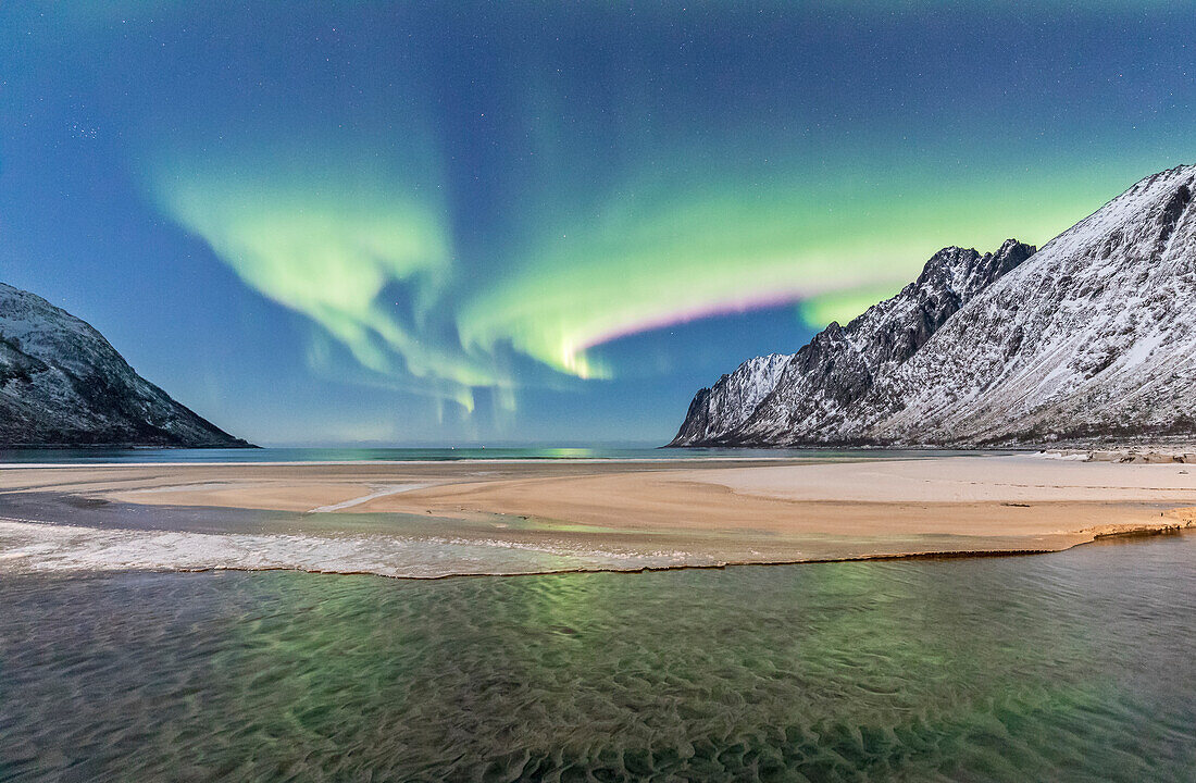 Grüne Lichter der Nordlichter (Aurora Borealis) spiegelt sich in der kalten See, umgeben von schneebedeckten Gipfeln, Ersfjord, Senja, Troms, Norwegen, Skandinavien, Europa