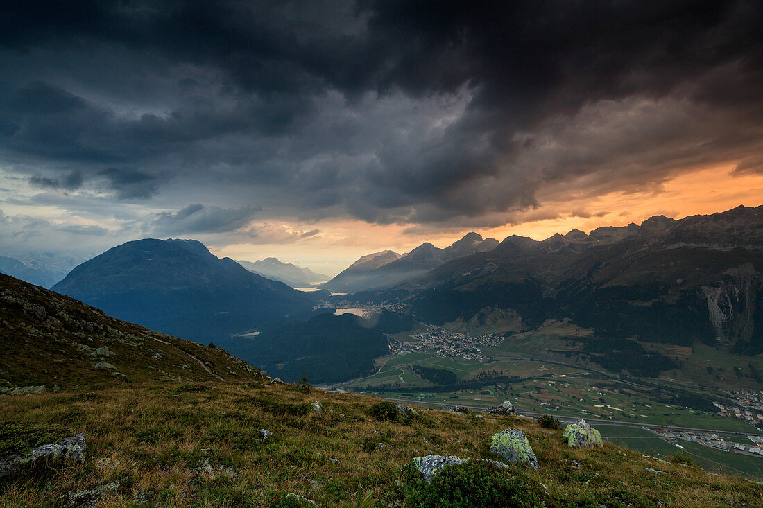 Dunkle Wolken und Sonnenuntergang Lichter rahmen die felsigen Gipfel von Muottas Muragl, St. Moritz, Kanton Graubünden, Engadin, Schweiz, Europa