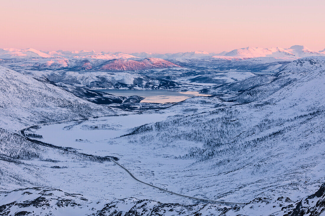 Rosa Himmel bei Sonnenuntergang auf der verschneiten Landschaft und gefrorenem Meer um Fjordbotn, Lysnes, Senja, Troms, Norwegen, Skandinavien, Europa
