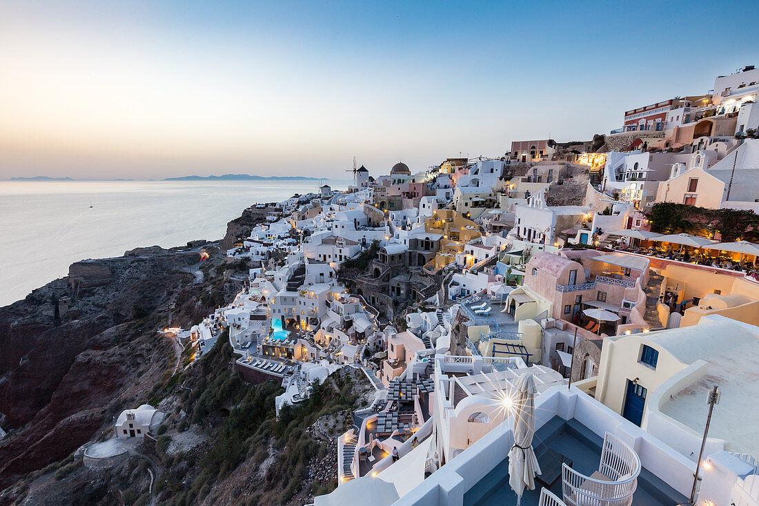 Sonnenuntergang Blick über die weiß getünchten Gebäude und Windmühlen von Oia, Santorini, Kykladen, griechische Inseln, Griechenland, Europa