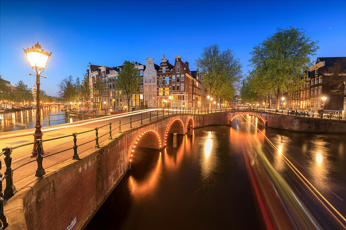 Dämmerung an typischen Gebäuden und Brücken, die sich in einem typischen Kanal, Amsterdam, Holland (Niederlande), Europa, widerspiegeln