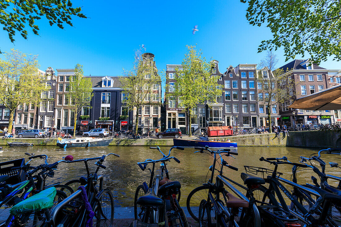 Fahrräder parkten am Ufer des Flusses Amstel und typische Häuser, Amsterdam, Holland (Niederlande), Europa