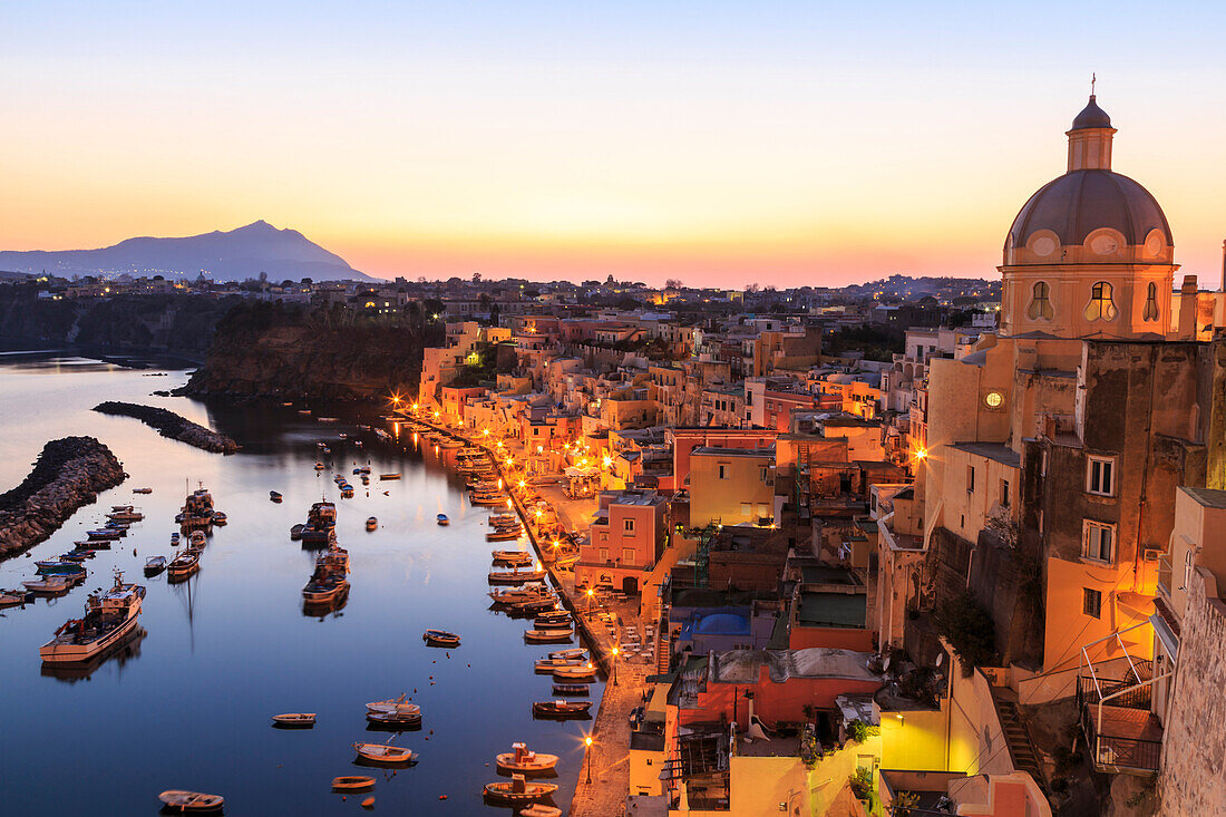 Marina Corricella, blue hour after sunset, fishing village, colourful houses, boats and church, Procida, Bay of Naples, Campania, Italy, Europe