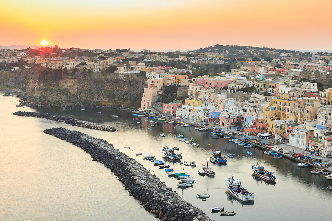 Marina Corricella sunset, fishing village, colourful fishermen's houses, boats and church, Procida Island, Bay of Naples, Campania, Italy, Europe