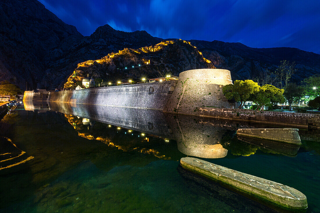 Ein Teil von Kotors alter Stadtmauer und beleuchteten Festungsmauern spiegelten sich während der Abend blauen Stunde, Montenegro, Europa
