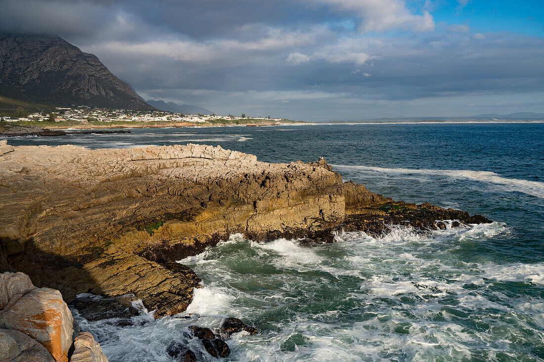 Seascape across stormy sea and rocks in setting sun at Sievers Point, Hermanus, South Africa, Africa