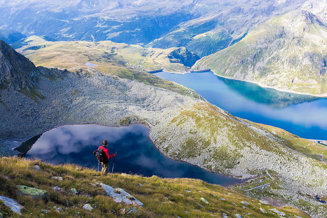 Hiker on the shore of Lago Nero admires the blue Lake Montespluga in summer, Chiavenna Valley, Valtellina, Lombardy, Italy, Europe
