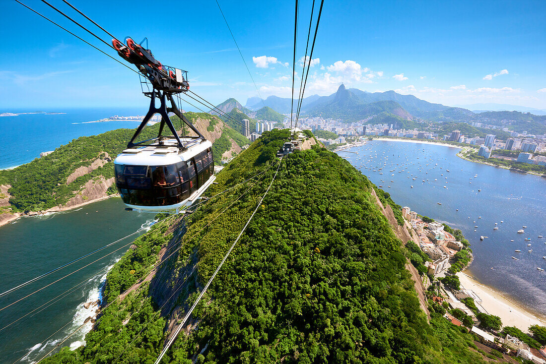 Eine Bewegungsunschärfe Seilbahn nähert sich der Station auf Sugarloaf Berg, mit weitläufigen Blick auf Rio de Janeiro hinter, Rio de Janeiro, Brasilien, Südamerika