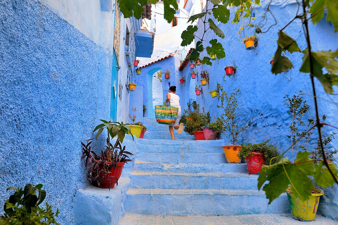 Girl run up the stairs in the medina of Chefchaouen, Tangeri-Tétuan, Morocco, North Africa