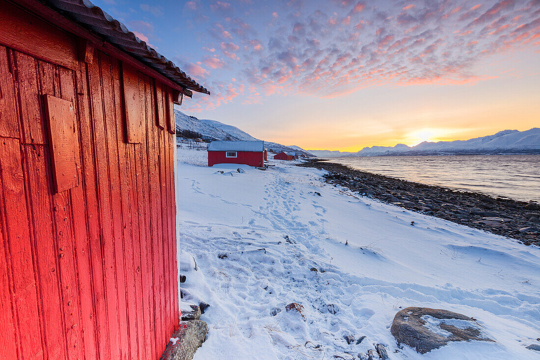 Sonnenuntergang unter den Fischerhäusern mit Blick auf den Fjord, Nordmannvik, Kafjord, Lyngen Alpen, Troms, Norwegen, Lappland, Europa