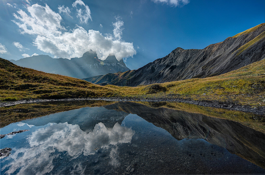 The Aiguille d'Arves at sunrise reflected in a small Alpine lake, Ecrins, Savoie, France