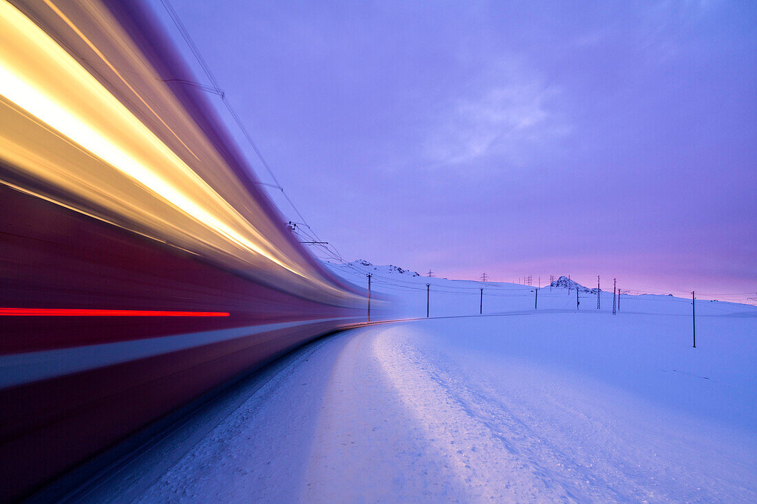 Bernina Express Zug fährt schnell in der verschneiten Landschaft im Morgengrauen Bernina Pass Kanton Graubünden Engadin Schweiz Europa