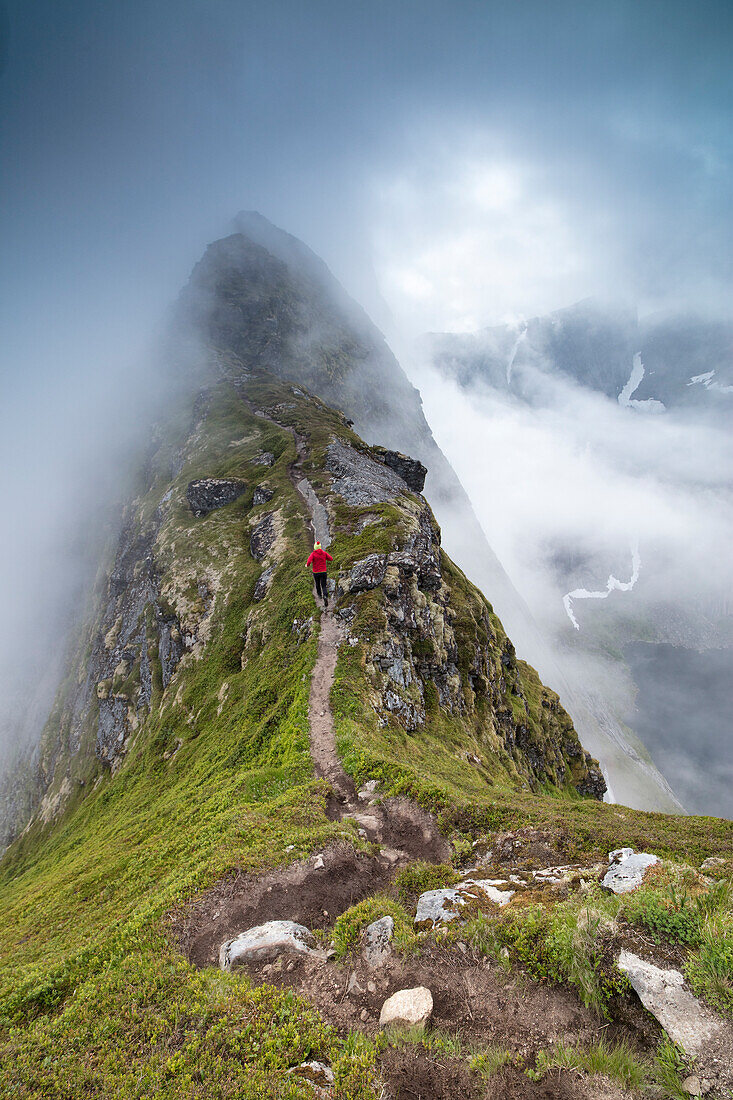 Wanderer führt auf einem steilen Weg zum Gipfel des Reinebringens unter dem Nebel Moskenes Lofoten Norwegen Norwegen