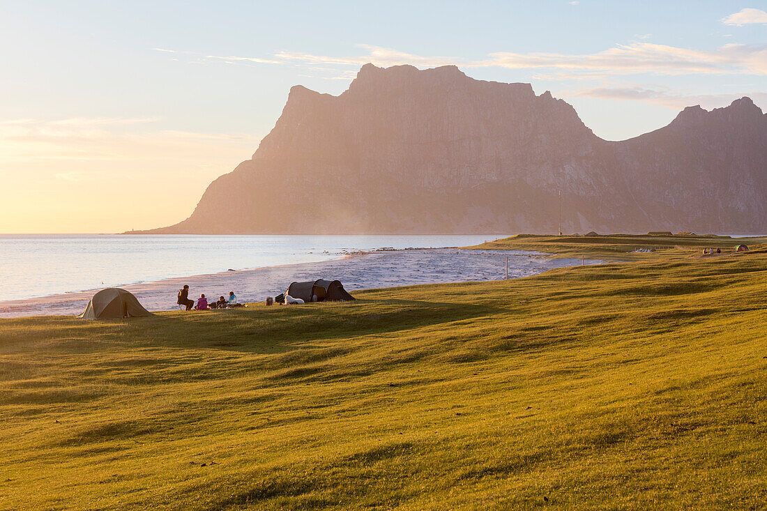 Camping tents on green meadows next to sea lighted up by midnight sun Uttakleiv Lofoten Islands Northern Norway Europe