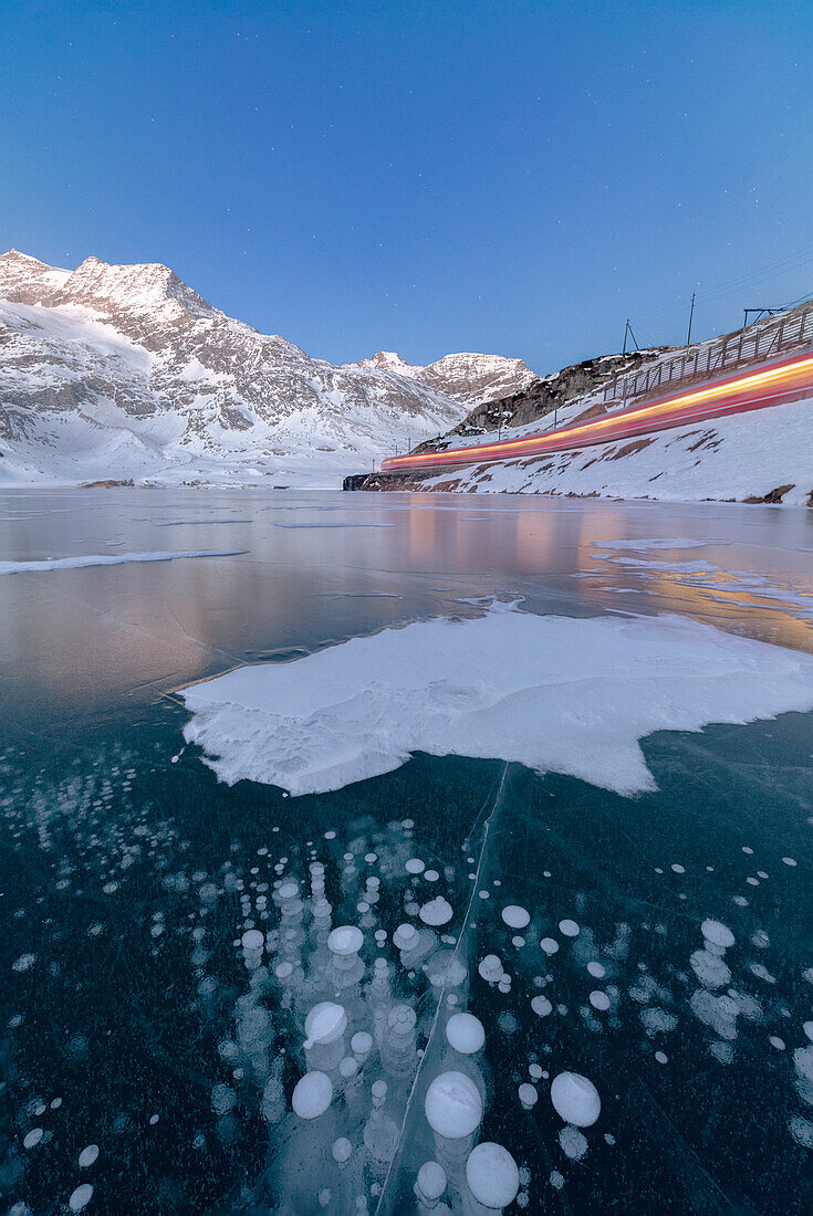 Der Bernina Express Zug fährt neben dem gefrorenen Lago Bianco Bernina Pass Kanton Graubünden Engadin Schweiz Europa
