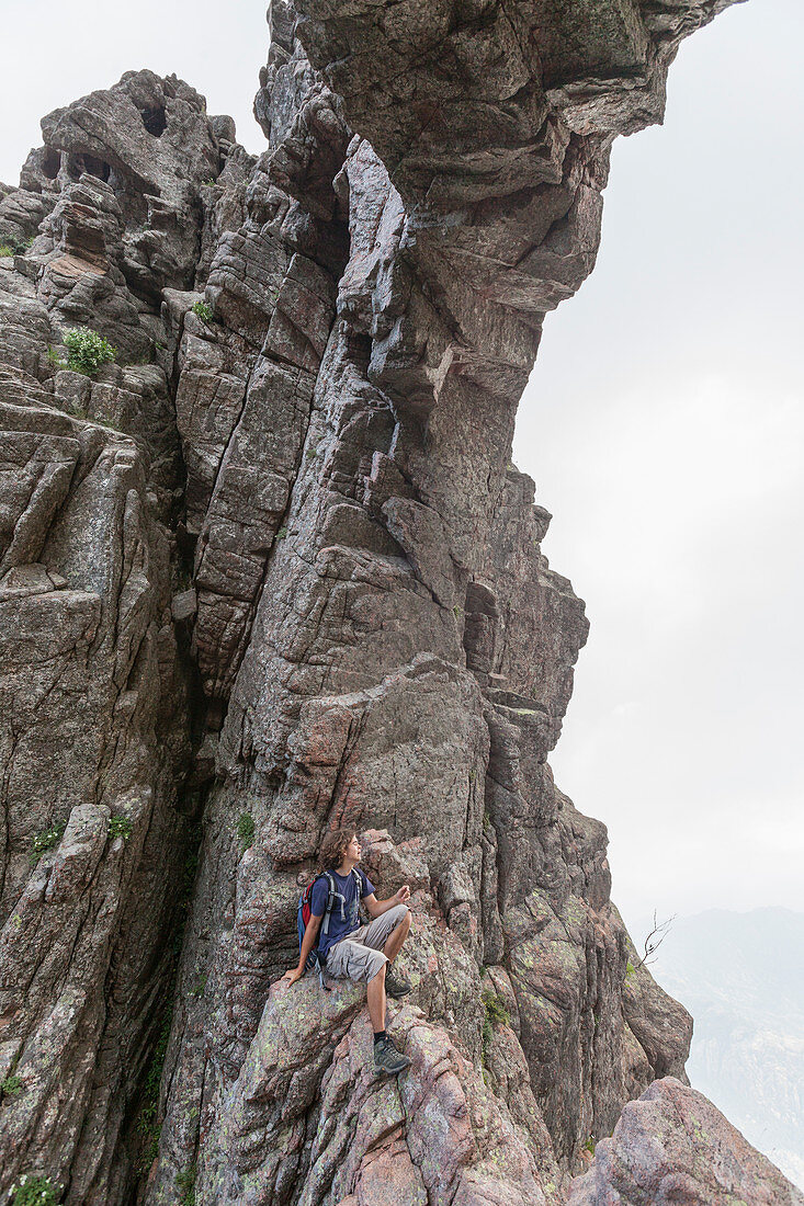 Wanderer sitzt auf den Felsen des Naturbogens Col de Bavella, Pass von Bavella, Solenzara Südkorsika Frankreich Europa