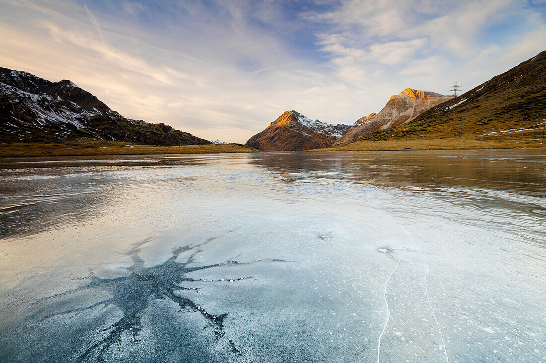 Sunset on the frozen Lej Nair surrounded by rocky peaks Bernina Pass Canton of Graubünden Engadine Switzerland Europe