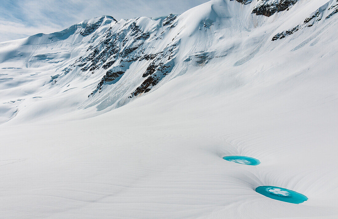 Zwei unglaubliche Wasserteiche, supraglaziale Seen, über den Schnee am Forni-Gletscher mit S, Matteo-Gipfel im Rücken